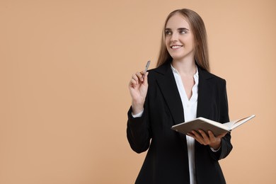 Happy young secretary with notebook and pen on beige background, space for text