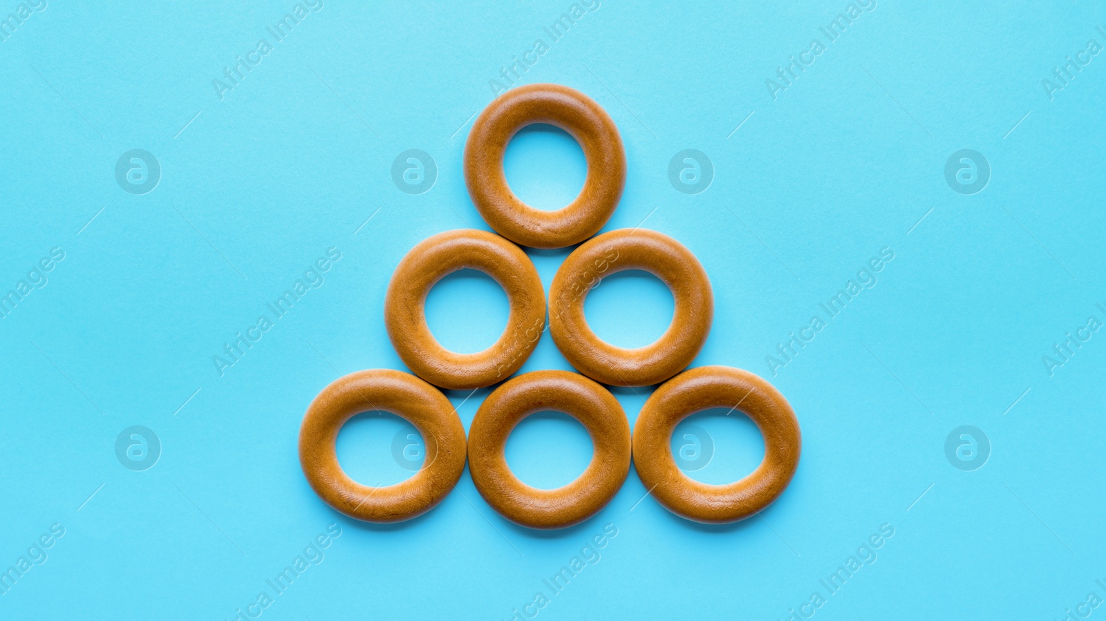 Photo of Tasty dry bagels (sushki) on light blue background, flat lay