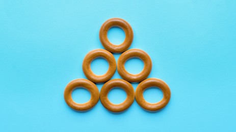 Tasty dry bagels (sushki) on light blue background, flat lay