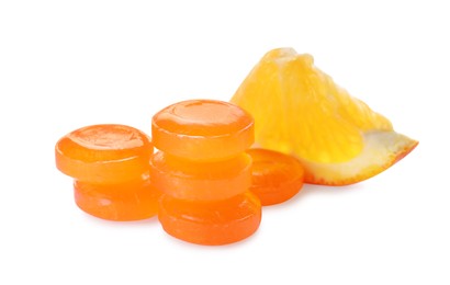 Photo of Many cough drops and slice of orange on white background