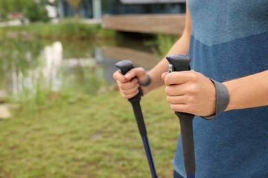 Photo of Man practicing Nordic walking with poles outdoors, closeup. Space for text