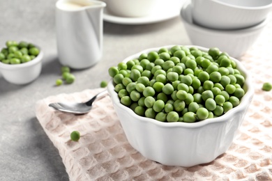 Photo of Bowl with delicious fresh green peas on table