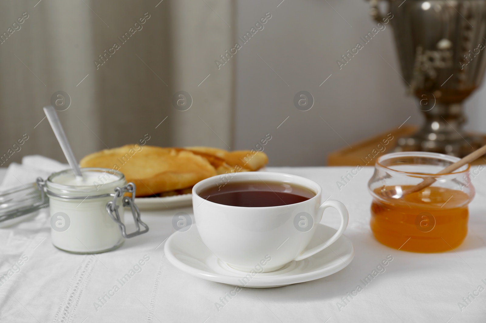 Photo of Vintage samovar, cup of hot drink and snacks served on table. Traditional Russian tea ceremony