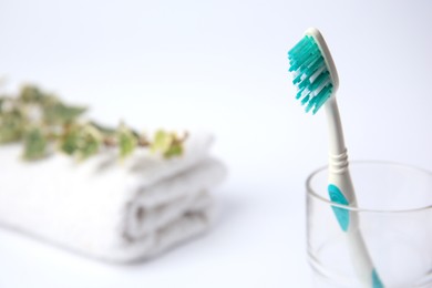 Light blue toothbrush in glass holder on white background, space for text
