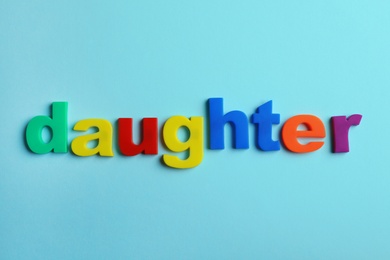 Photo of Word DAUGHTER of magnetic letters on color background, top view