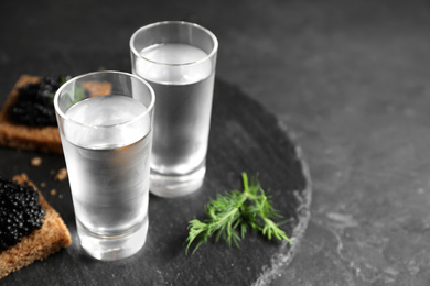 Photo of Cold Russian vodka with snacks on black table, closeup