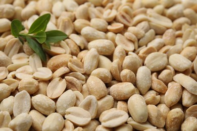 Photo of Many fresh peeled peanuts and leaves as background, closeup