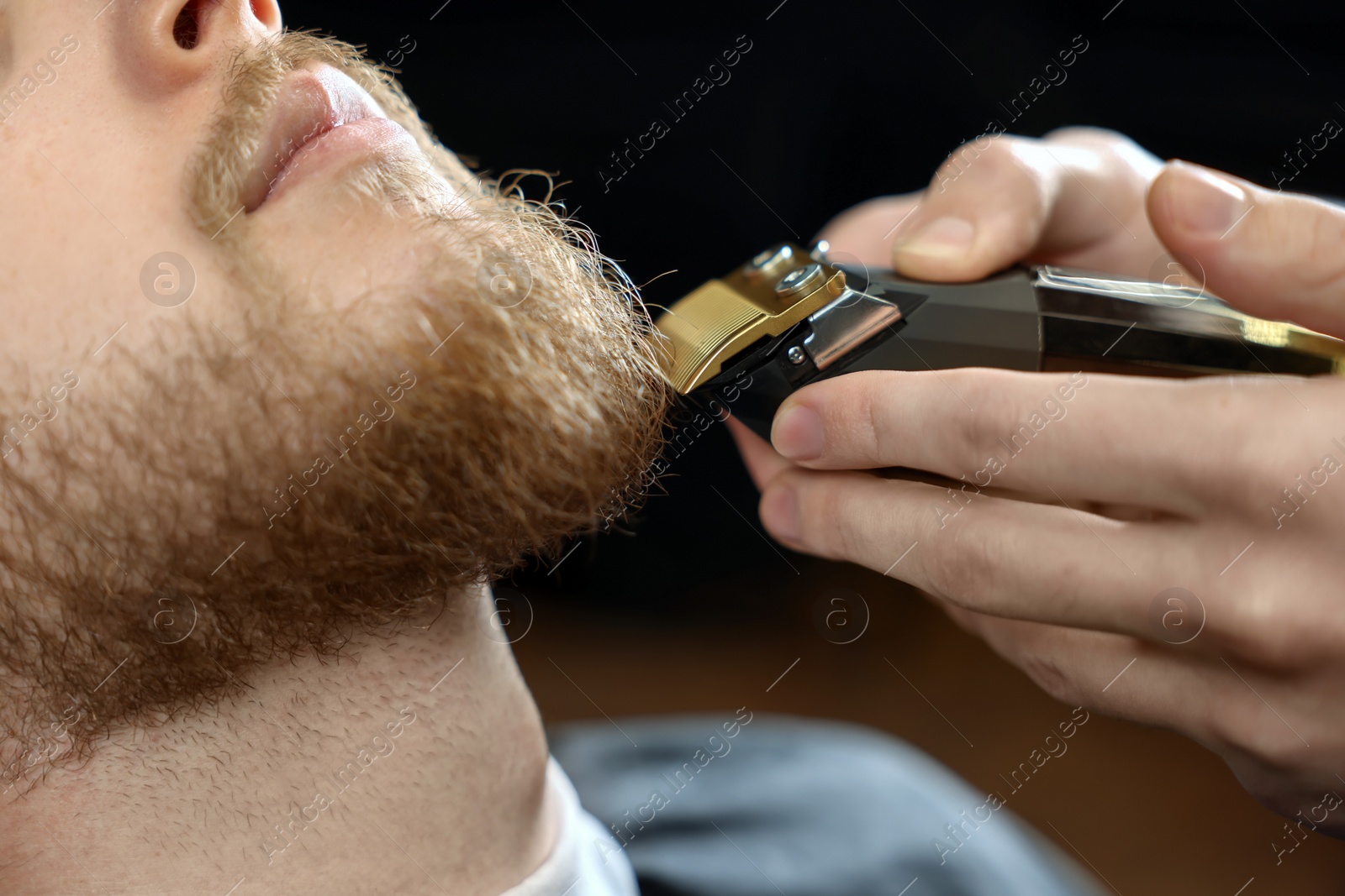 Photo of Professional hairdresser working with bearded client in barbershop, closeup