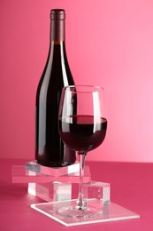 Stylish presentation of delicious red wine in bottle and glass on pink background