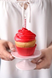 Photo of Woman holding stand with birthday cupcake, closeup