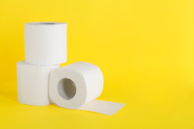 Photo of Many soft toilet paper rolls on yellow background. Space for text