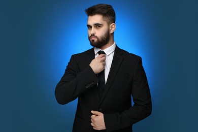 Handsome businessman in suit and necktie on blue background