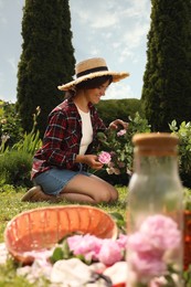 Photo of Woman collecting tea roses in garden on sunny day