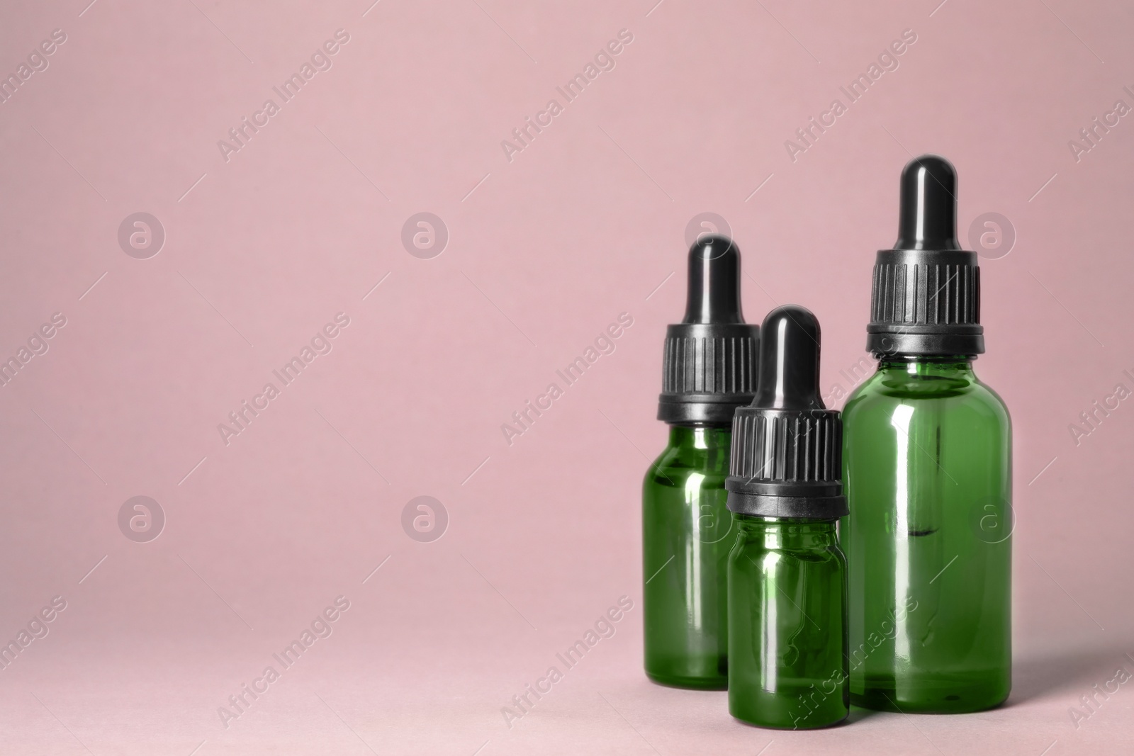 Photo of Cosmetic bottles of essential oils on color background. Space for text