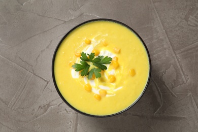 Delicious creamy corn soup served on grey table, top view