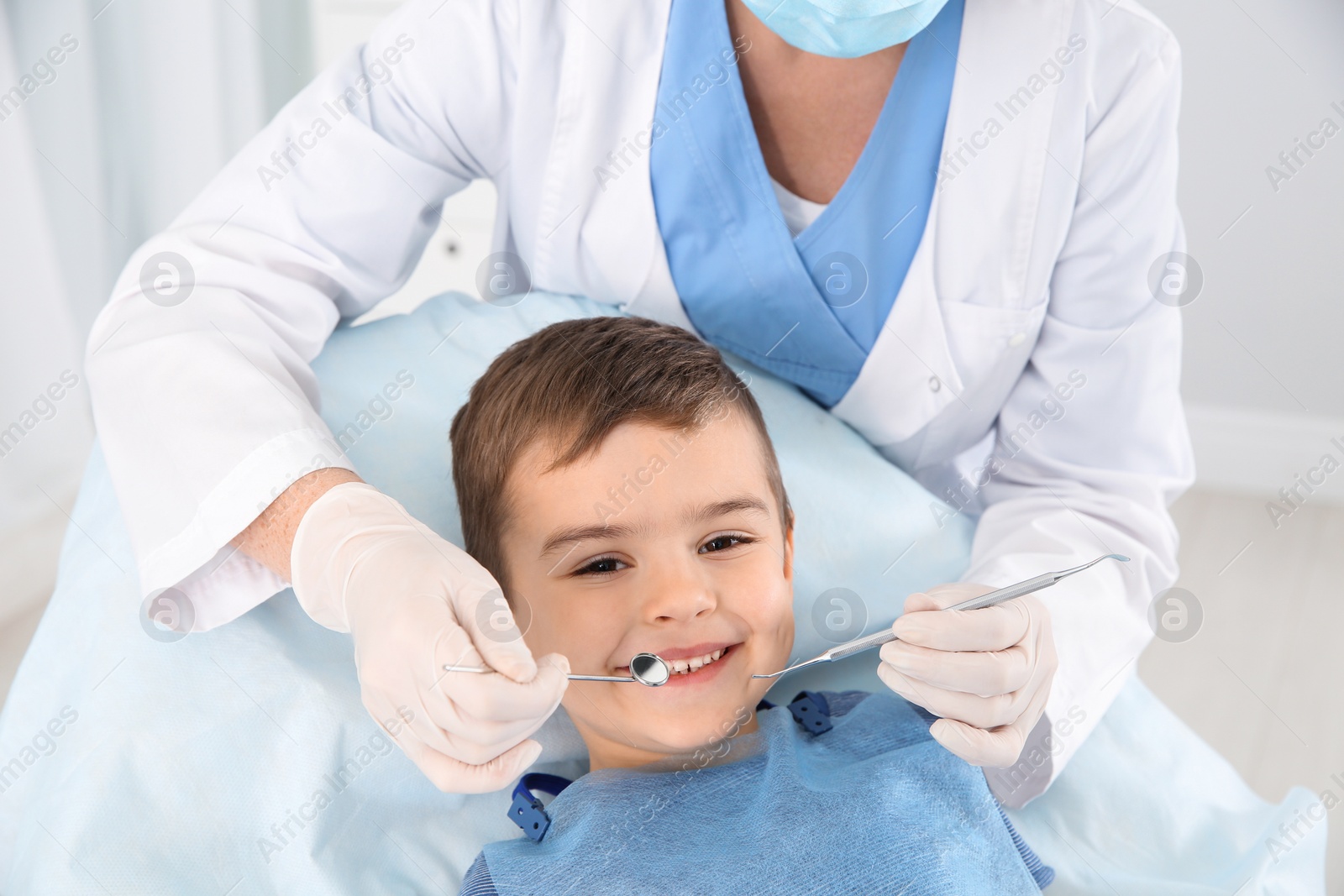 Photo of Dentist examining cute boy's teeth in modern clinic