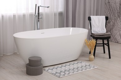 Stylish bathroom interior with soft bath mat and tub