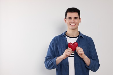 Photo of Happy volunteer holding red heart with hands on light background. Space for text