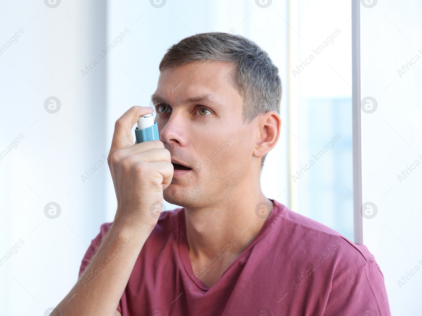 Photo of Young man using asthma inhaler at home