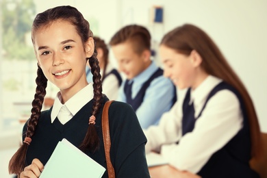 Happy teen girl with backpack in school classroom