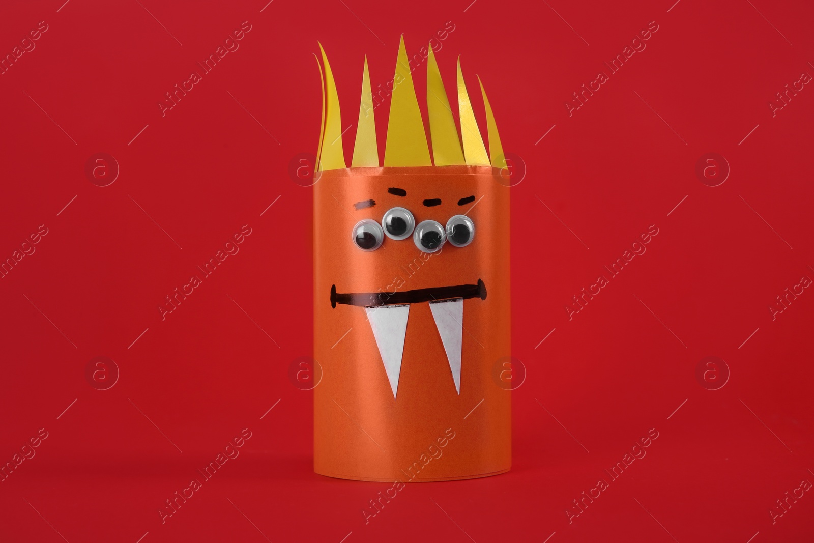 Photo of Funny orange monster on red background. Halloween decoration