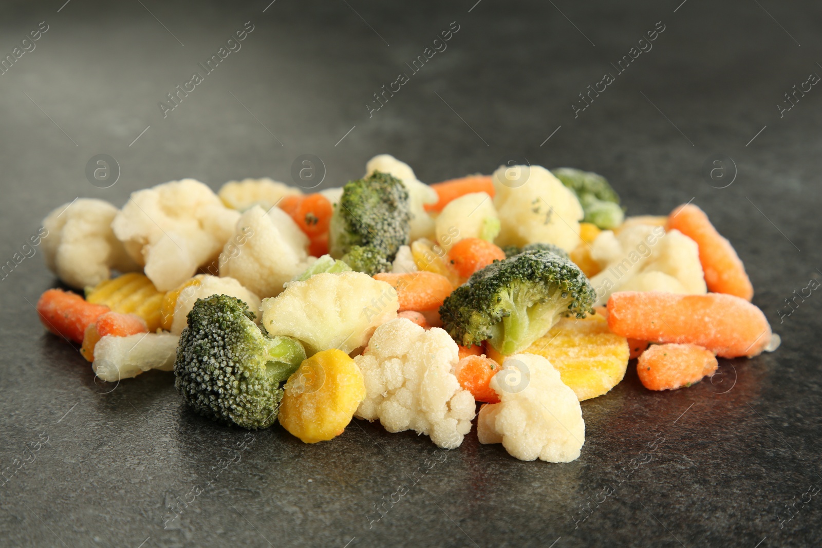 Photo of Mix of different frozen vegetables on gray table, closeup