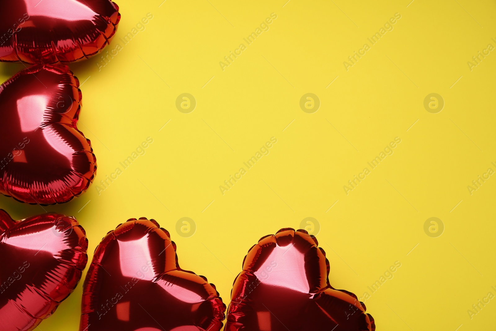 Photo of Red heart shaped balloons on yellow background, flat lay with space for text. Valentine's Day celebration