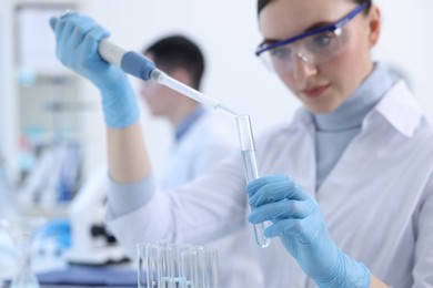 Scientist dripping sample into test tube in laboratory, selective focus