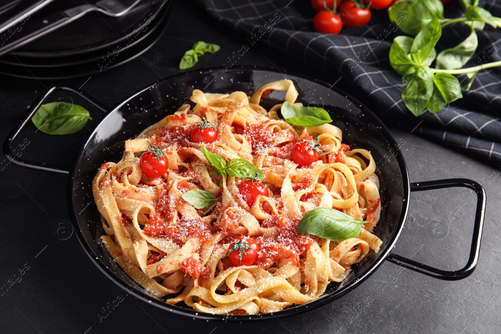 Photo of Tasty pasta with tomatoes, cheese and basil on black table