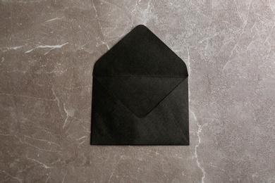 Photo of Black paper envelope on marble background, top view