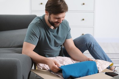 Photo of Happy man opening parcel at home. Internet shopping