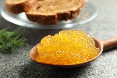 Photo of Fresh pike caviar in spoon on grey table, closeup