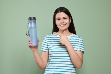 Young woman with bottle of water on green background