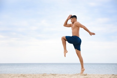 Muscular man doing exercise on beach, space for text. Body training