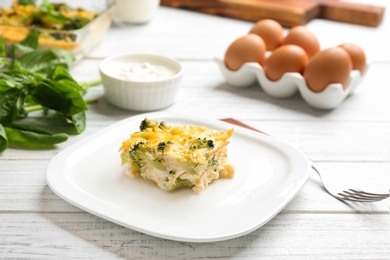 Photo of Piece of tasty broccoli casserole on white wooden table