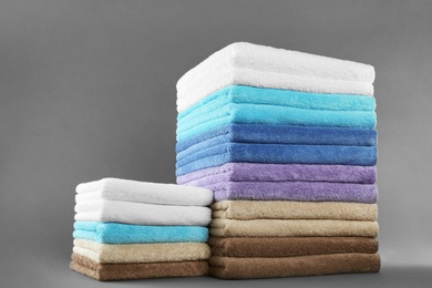 Different fresh soft terry towels on grey background