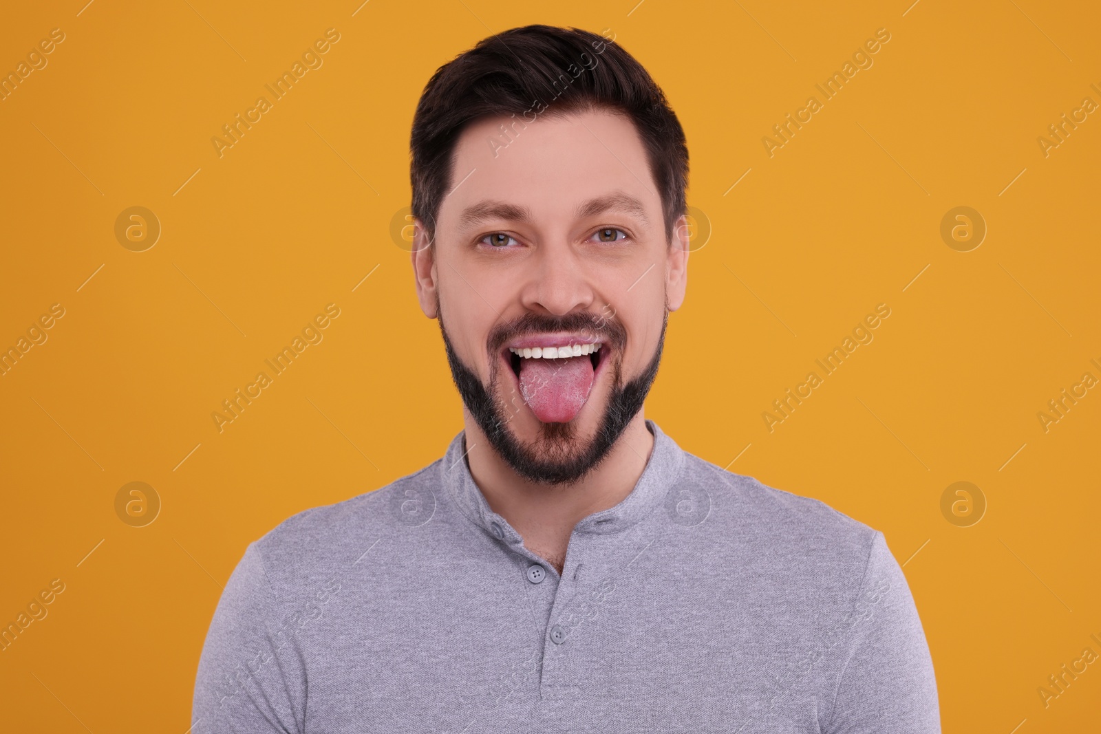 Photo of Happy man showing his tongue on orange background