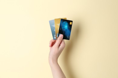 Photo of Woman holding credit cards on pale yellow background, closeup