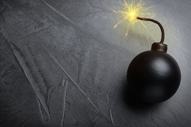 Image of Old fashioned black bomb with lit fuse on grey table, top view. Space for text