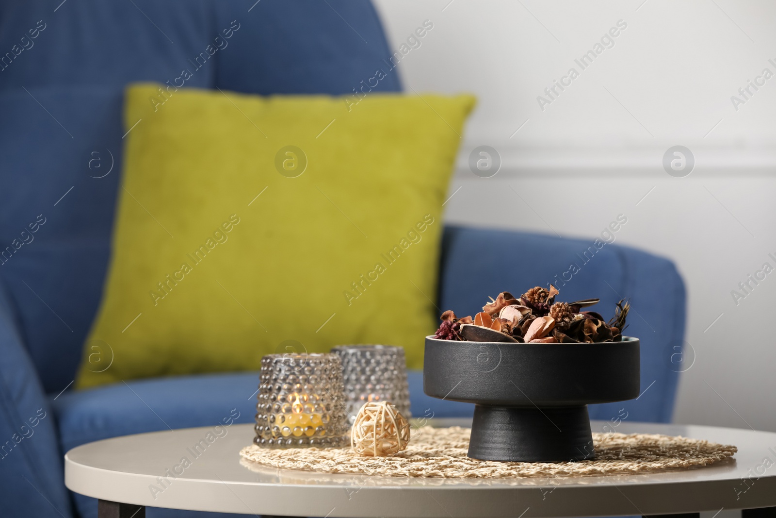 Photo of Aromatic potpourri of dried flowers and burning candles on table indoors