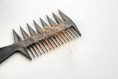 Photo of Comb with lost hair on light table. Alopecia problem