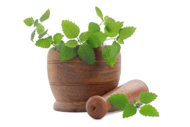 Wooden mortar with pestle and fresh green lemon balm leaves isolated on white