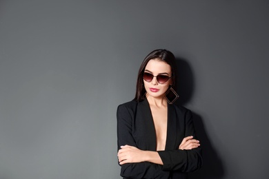 Photo of Beautiful woman wearing jacket and sunglasses on black background, space for text