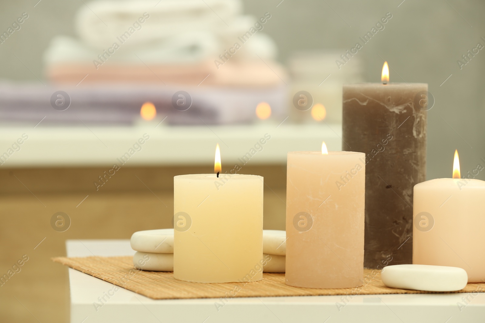 Photo of Beautiful spa composition with burning candles and stones on white table in wellness center