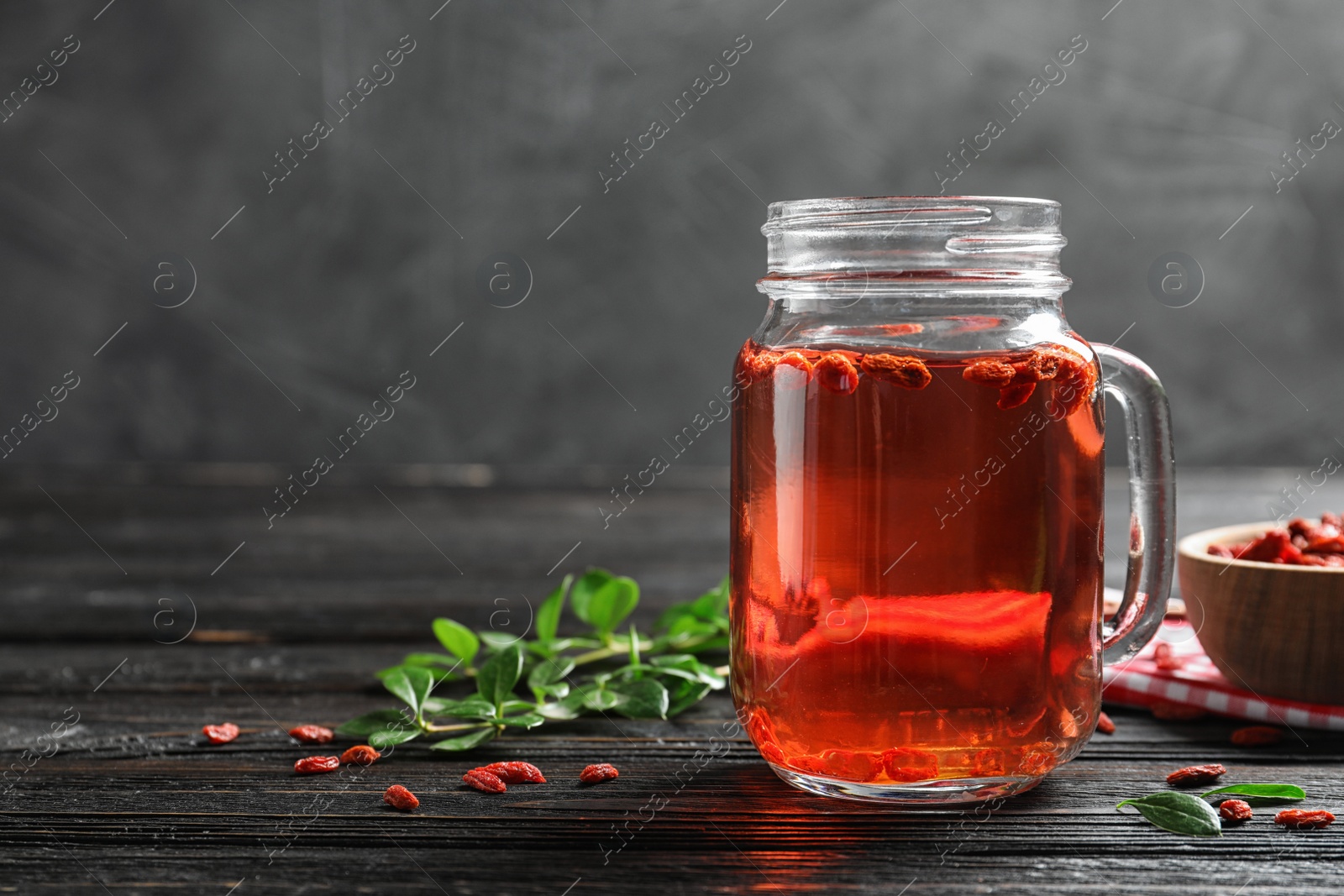 Photo of Healthy goji juice in mason jar on wooden table, space for text