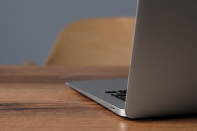 Photo of Modern laptop on wooden table indoors, closeup. Space for text