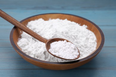 Photo of Bowl and spoon of natural starch on light blue wooden table, closeup