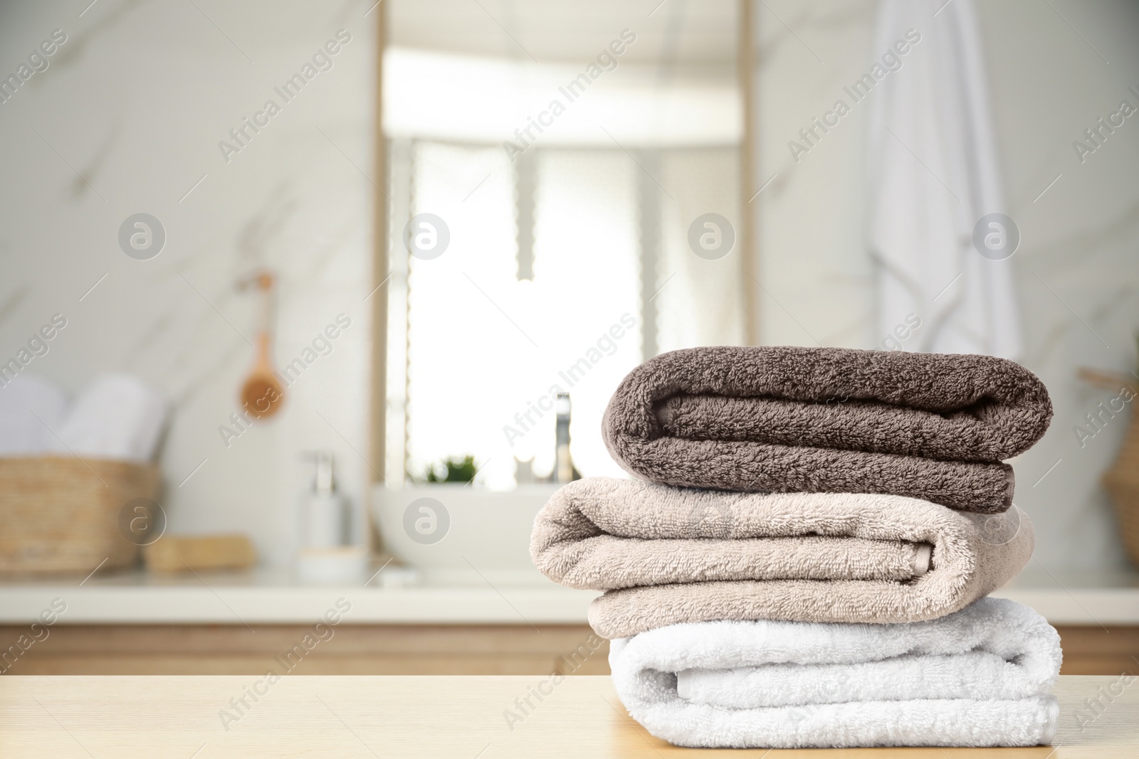 Image of Fresh towels on wooden table in bathroom. Space for text