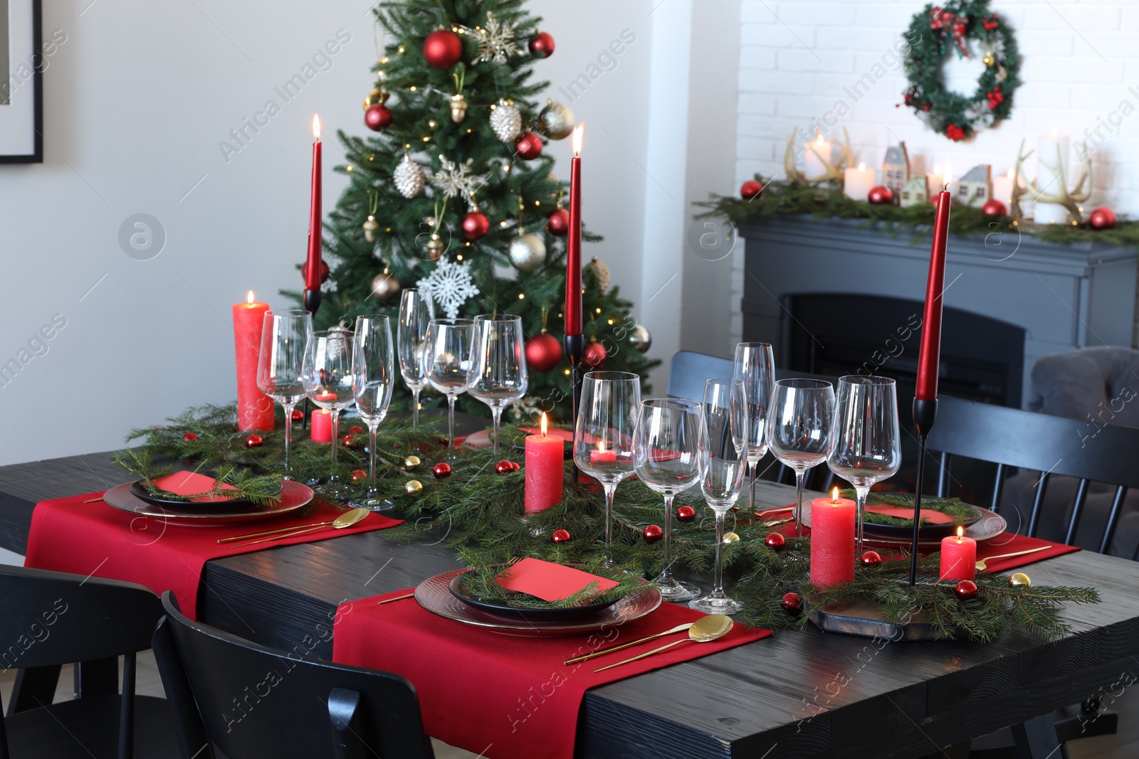 Photo of Elegant Christmas table setting with dishware and burning candles in festively decorated room