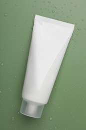 Photo of Tube of face cleansing product on green background, top view